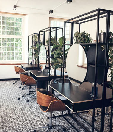 modern industrial aesthetic hair salon interior with round mirrors and wooden swivel chairs green plants
