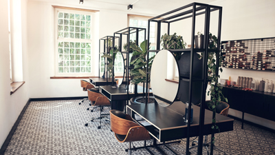 modern industrial aesthetic of hair salon with wooden chairs round mirrors and colour boxes stacked on the wall